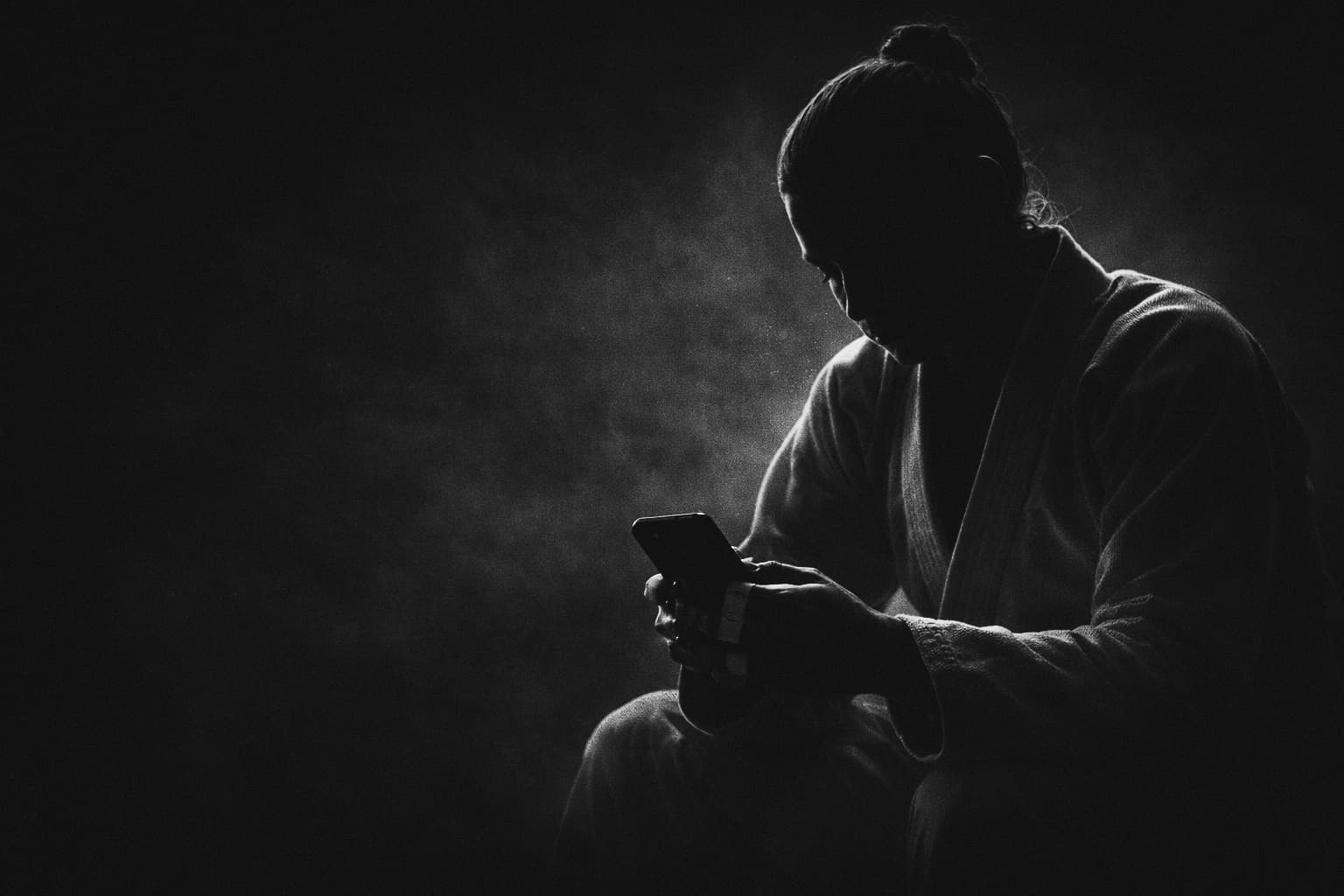 BJJ practitioner in gi studying Grapla on iPhone